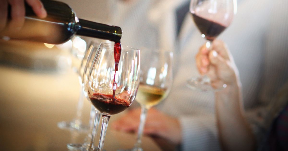 ไวน์แดงขายดี 10 ขวดวางเรียงกันพร้อมแก้วชิม มีทั้ง Shiraz Carmenère และ Cabernet